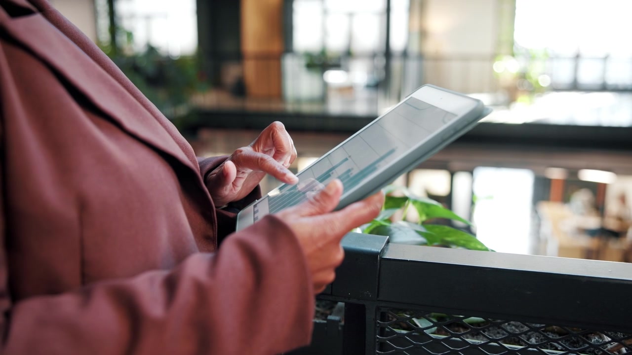 Donna d'affari che analizza dati finanziari su tablet in ufficio.