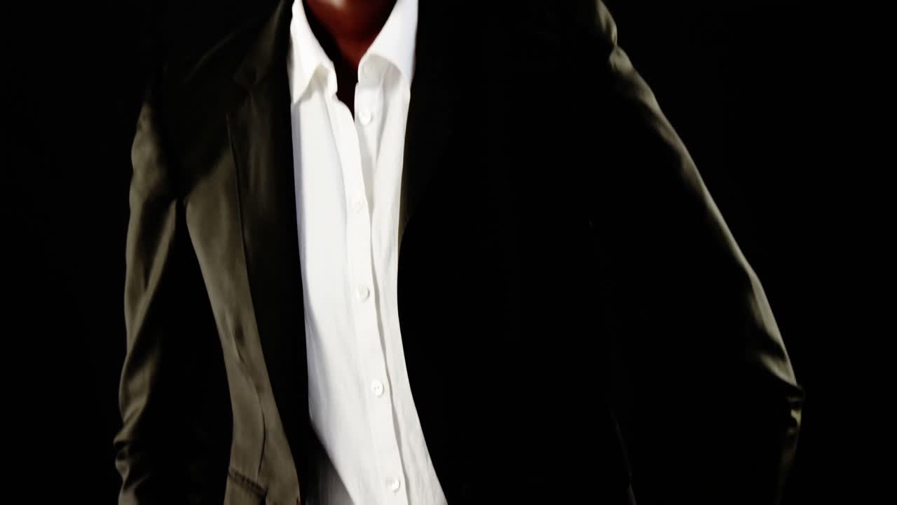 hombre andrógino posando en blazer contra un fondo negro