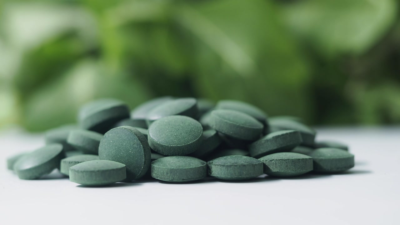 Green Chlorella Spirulina Tablets on White Background