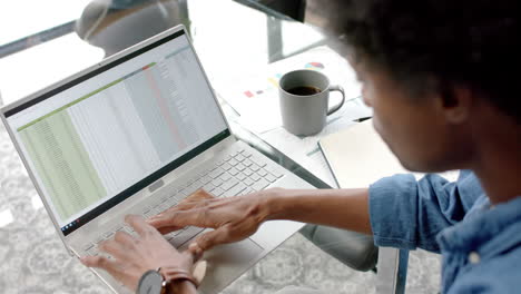 African-american-casual-businessman-sitting-at-desk-using-laptop-at-home,-slow-motion