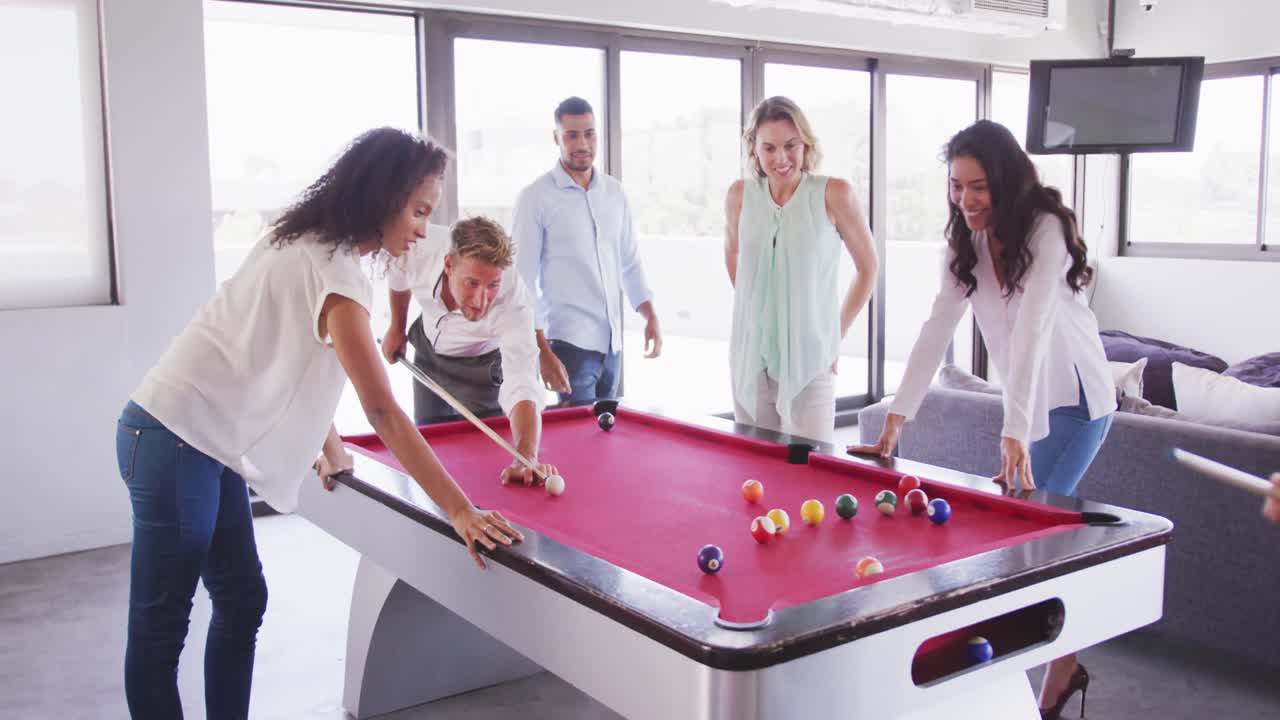 Professional businesspeople playing billiards in modern office in slow motion