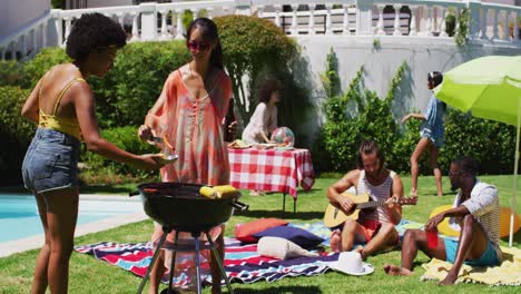 diverse group of friends having barbecue and talking at a pool party