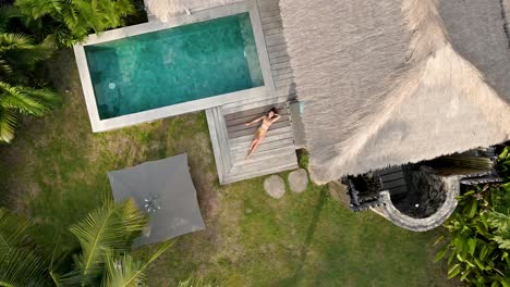 girl lying and resting on terrace of luxury villa with pool during holidays on gili air,indonesia