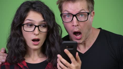 young couple using phone and looking shocked together