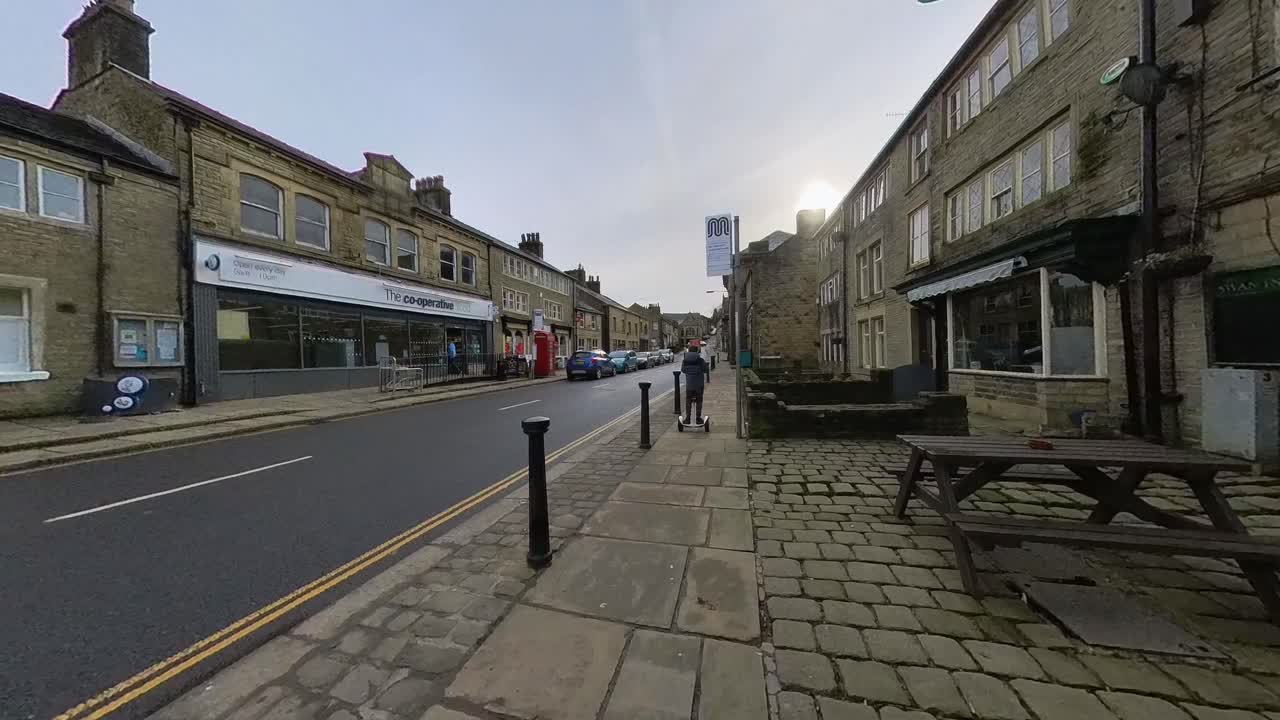 Dreng kører gennem gaderne i en landsby på en segway, hoverboard, Delph landsby, Oldham, Storbritannien