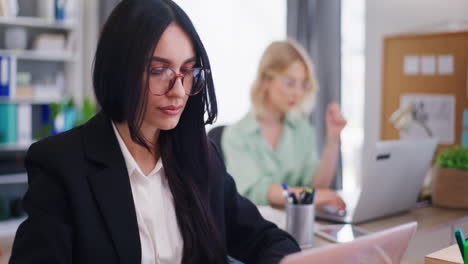 mujer pensativa y concentrada trabajando en una computadora portátil