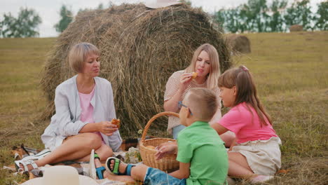 lovely family enjoying lunch outdoors in an open field, with the little girl selecting a pastry from the picnic basket, surrounded by nature and the warmth of a sunny day