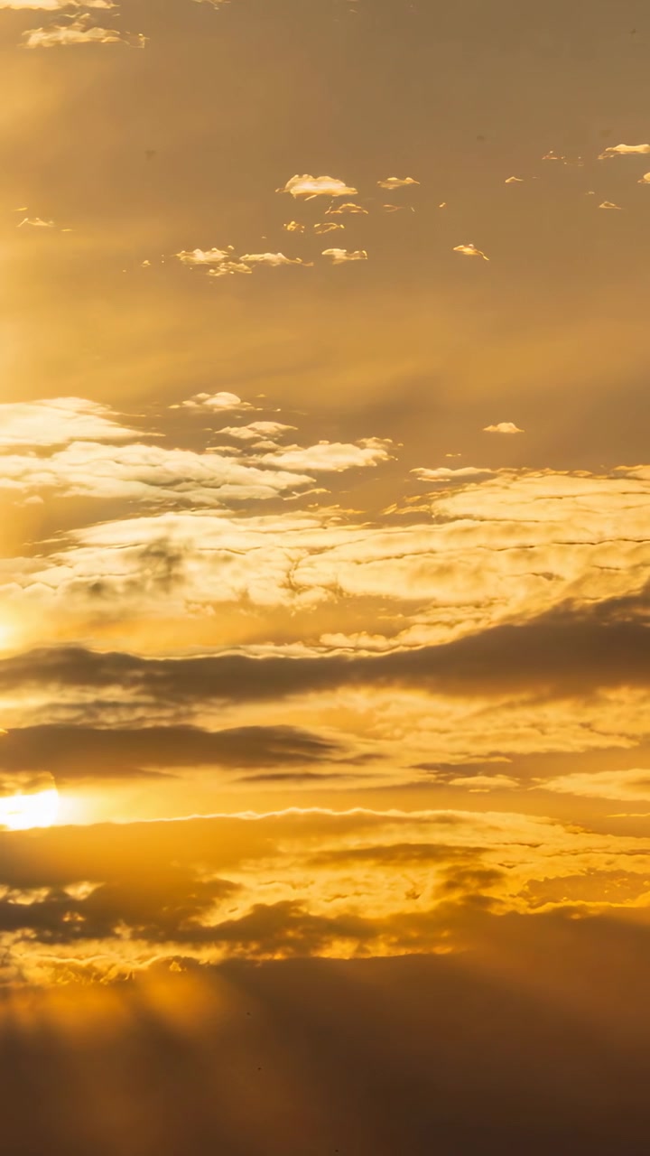 Vertikales Video: Bilder fangen goldenen Himmel bei Sonnenaufgang ein, Wolken verschieben sich und Strahlen verändern das Bild.