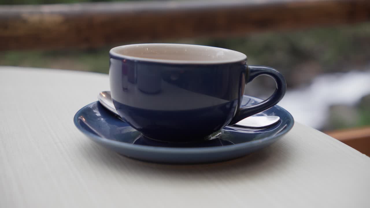 A cup of coffee resting on a saucer, shot in soft lighting with a blurred background