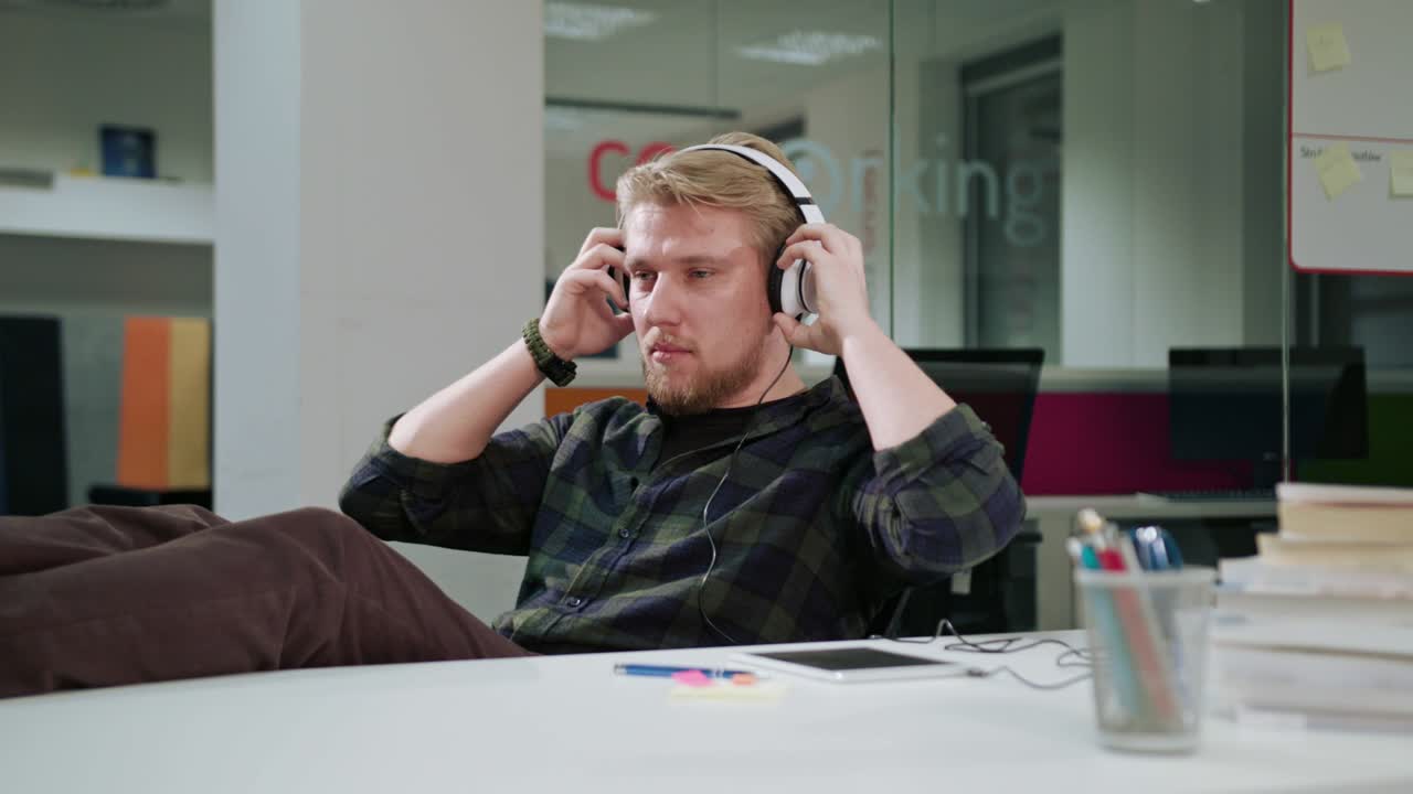 A Young Man Using a Tablet and Listening to Music