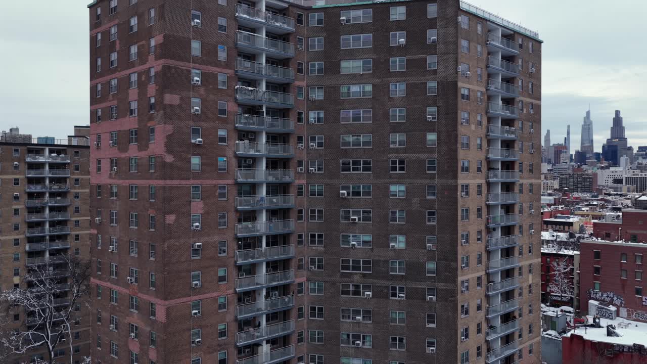 Vista aérea ascendente de edificios de apartamentos residenciales en Nueva York durante el invierno, revelando el horizonte de Manhattan de fondo. Torre residencial histórica.