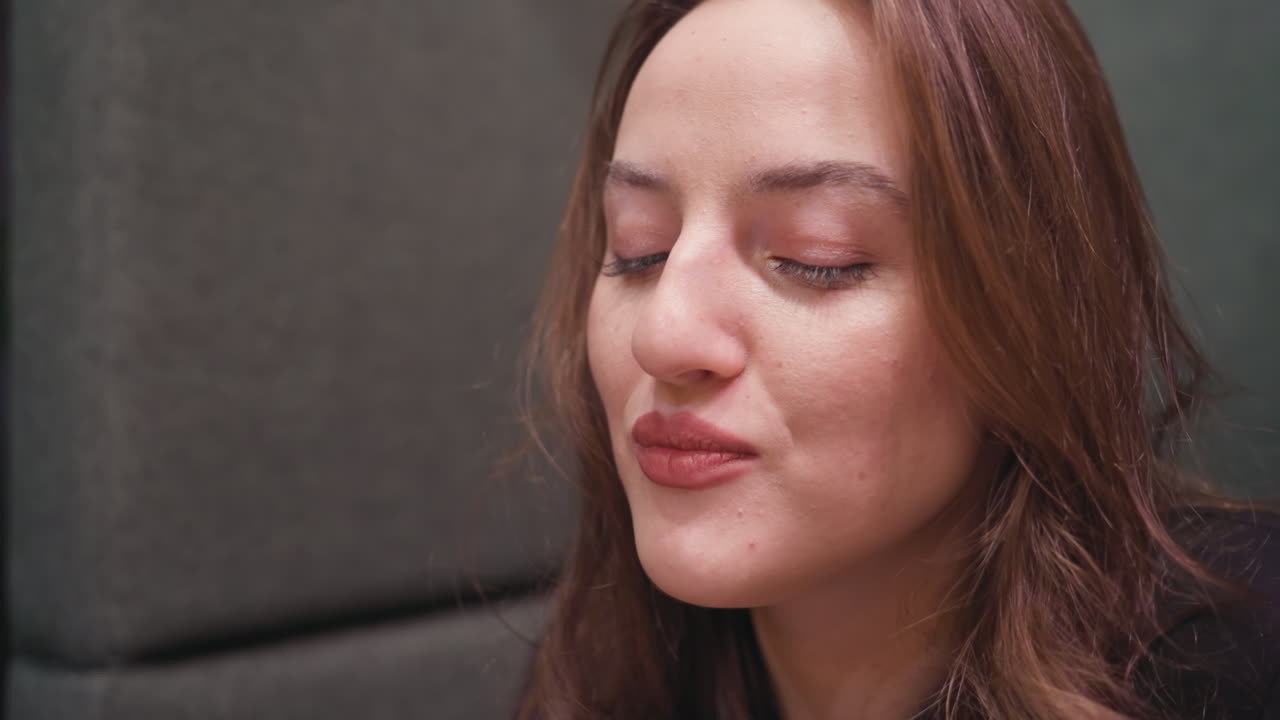 Closeup of lady eating delicious waffles using fork with gentle smile, eyes closed in enjoyment, showcasing cozy and satisfying dining moment filled with delight and flavor on soft background