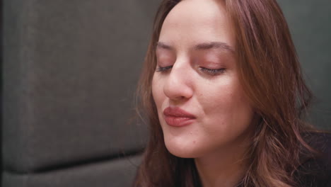 closeup of lady eating delicious waffles using fork with gentle smile, eyes closed in enjoyment, showcasing cozy and satisfying dining moment filled with delight and flavor on soft background