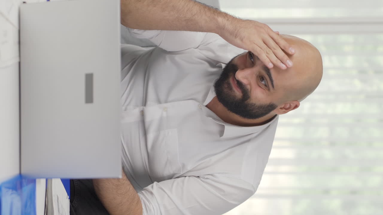 Video verticale di un uomo che lavora da casa confuso.
