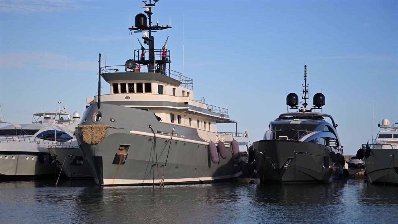 Collezione di yacht di lusso e motoscafi ormeggiati fianco a fianco nel porto turistico di Cannes sotto un cielo azzurro e limpido.