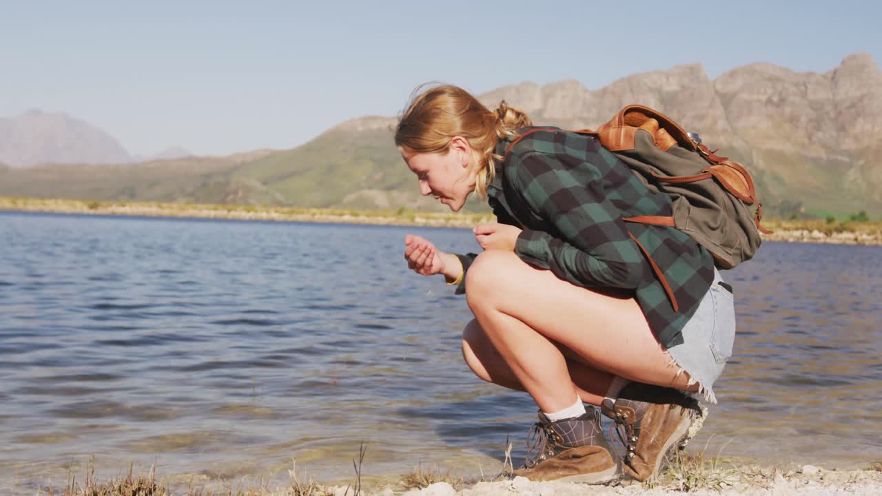 mujer caucásica junto a un lago en la naturaleza.