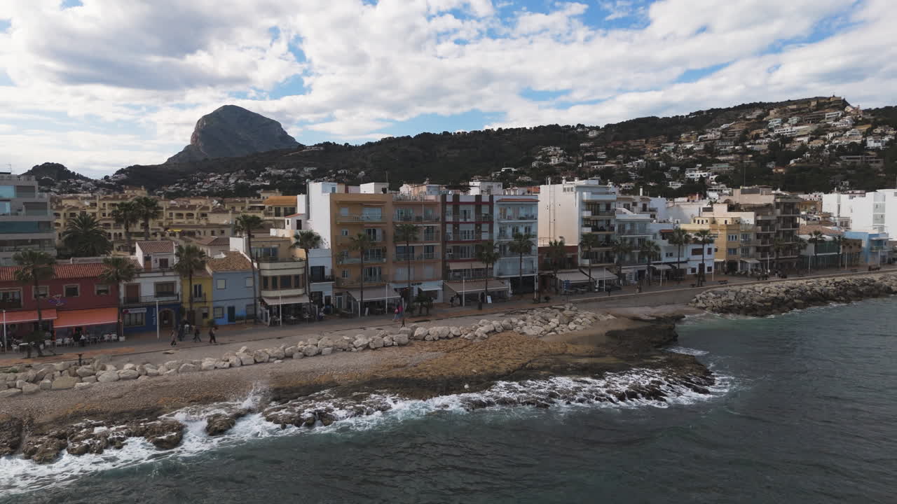 Evening light falls over Xabia harbor with boats docked beside shoreline
