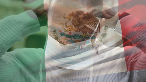 animation of flag of mexico waving over man wearing face mask during covid 19 pandemic