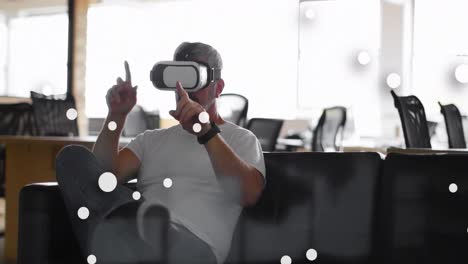 animation of spots over caucasian businessman using vr headset in office