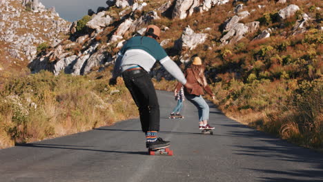 jóvenes amigos multiétnicos longboarding juntos montando patineta crucero cuesta abajo en la carretera del campo divirtiéndose disfrutando de unas vacaciones de verano relajadas