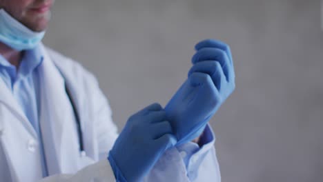 caucasian male doctor wearing medical gloves and face mask