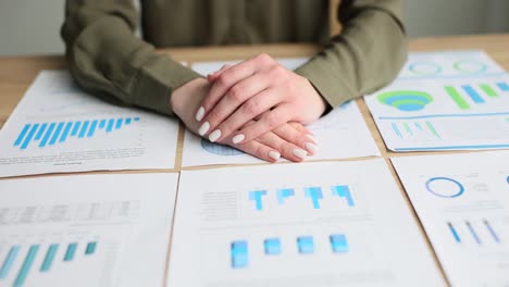 person's hands resting on desk among business charts and graphs