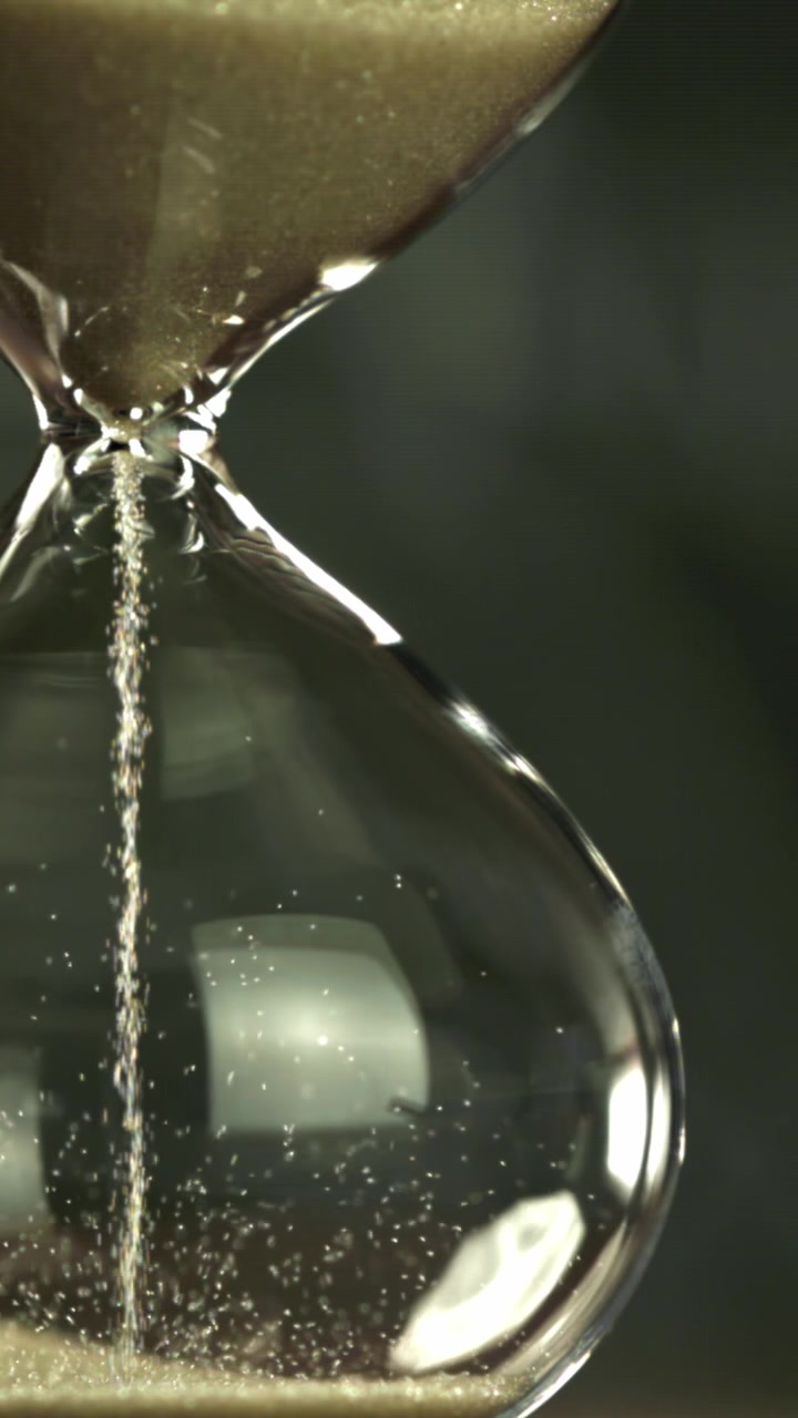 Golden Sand Falling Through a Glass Hourglass