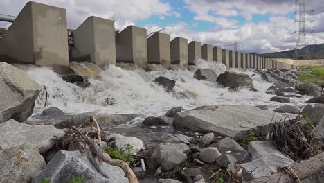 Agua-Que-Fluye-A-Través-De-Una-Puerta-De-Presa-Hacia-Rocas-En-Cámara-Lenta