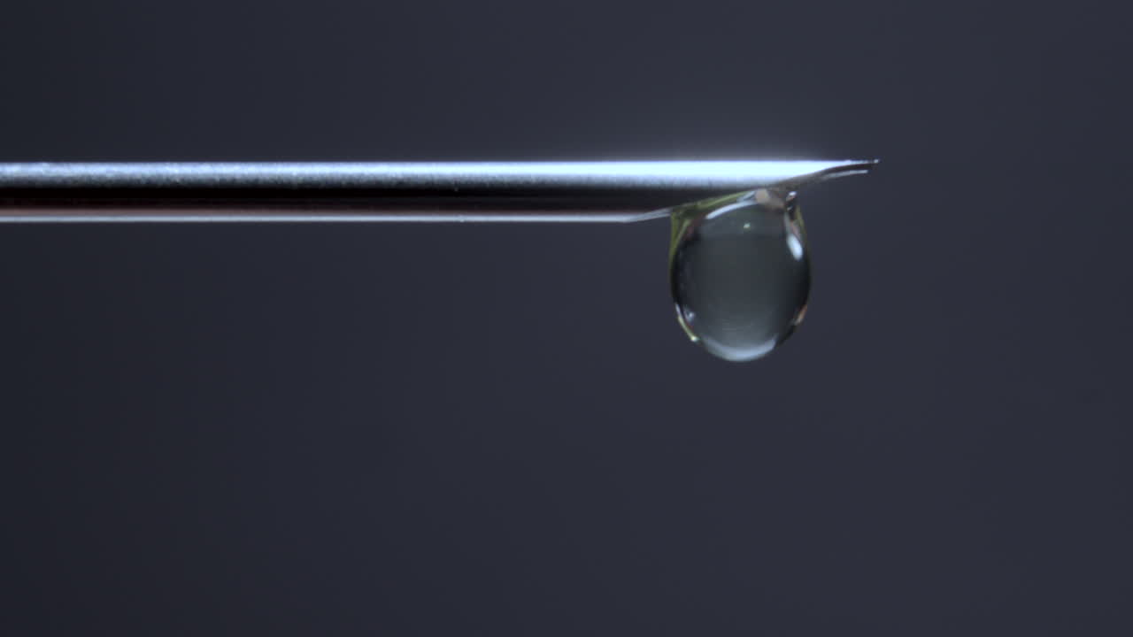 aguja de la jeringa goteando en una iluminación estilizada de bajo tono