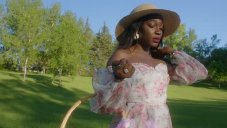close up of black lady in dress with picnic basket over arm walking in park