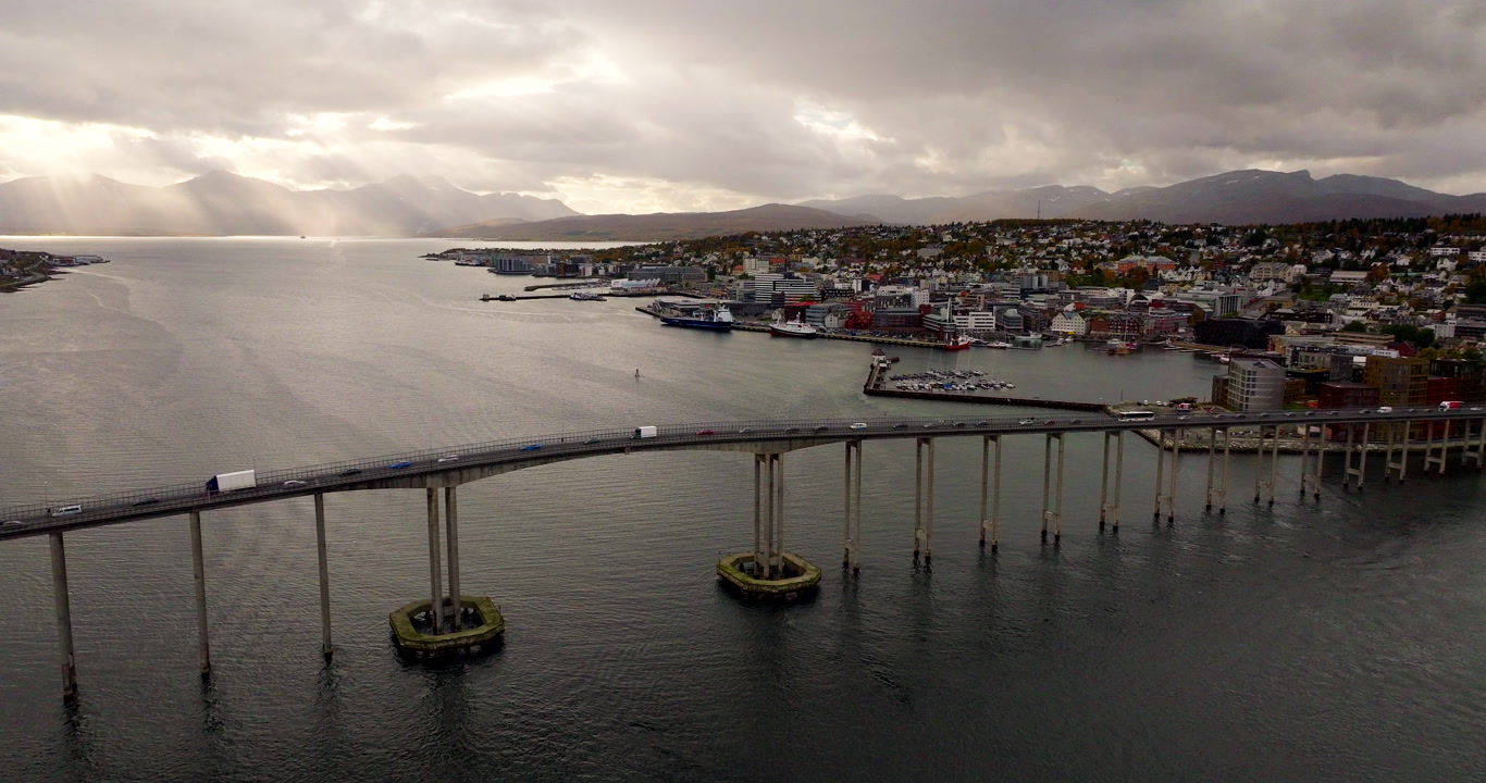 High drone view of Tromso bridge traffic and city harbor in background in autumn