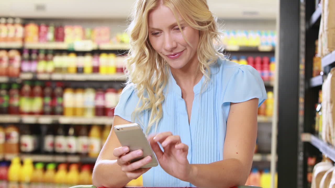 Smiling blonde shopping and using smartphone