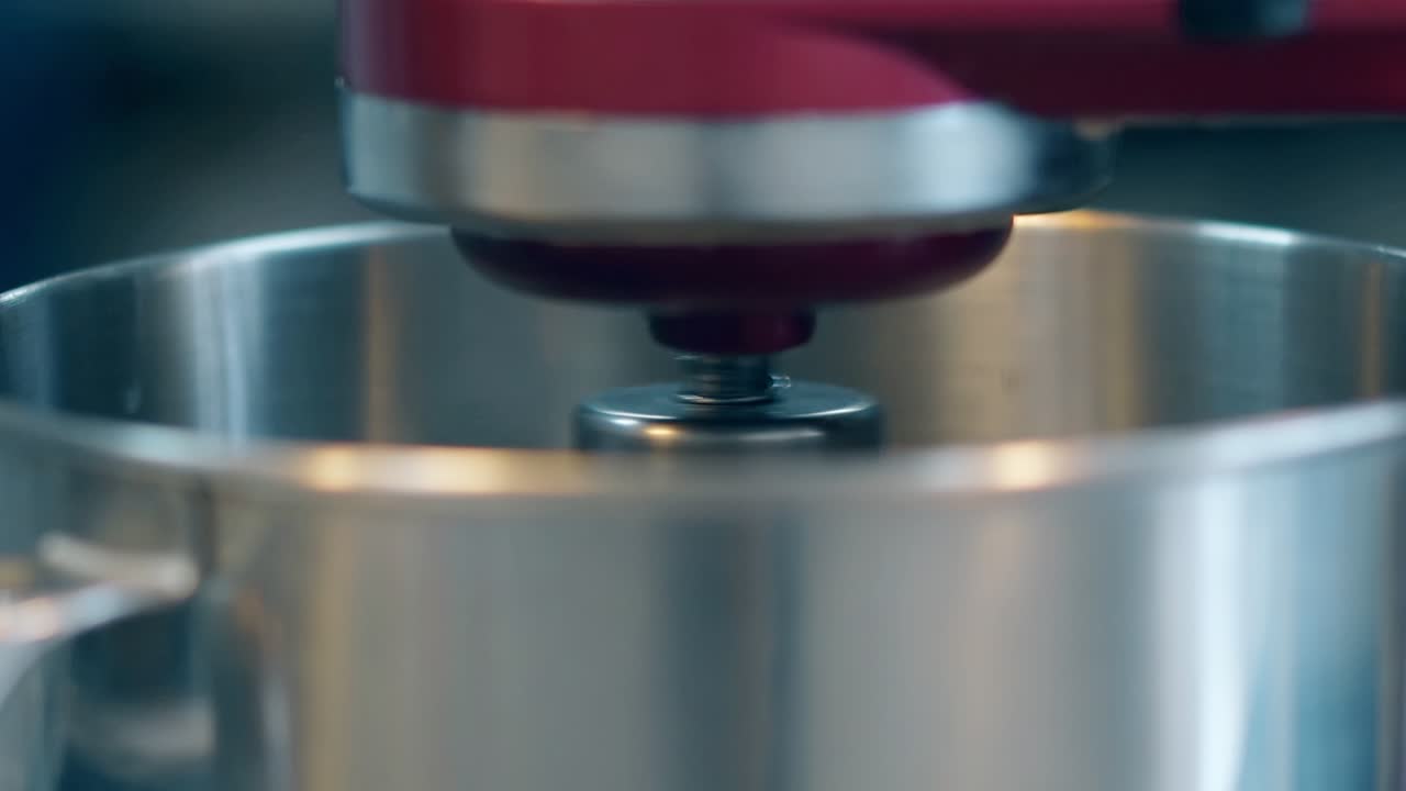 el mezclador rojo gira y prepara comida en un gran cuenco de metal