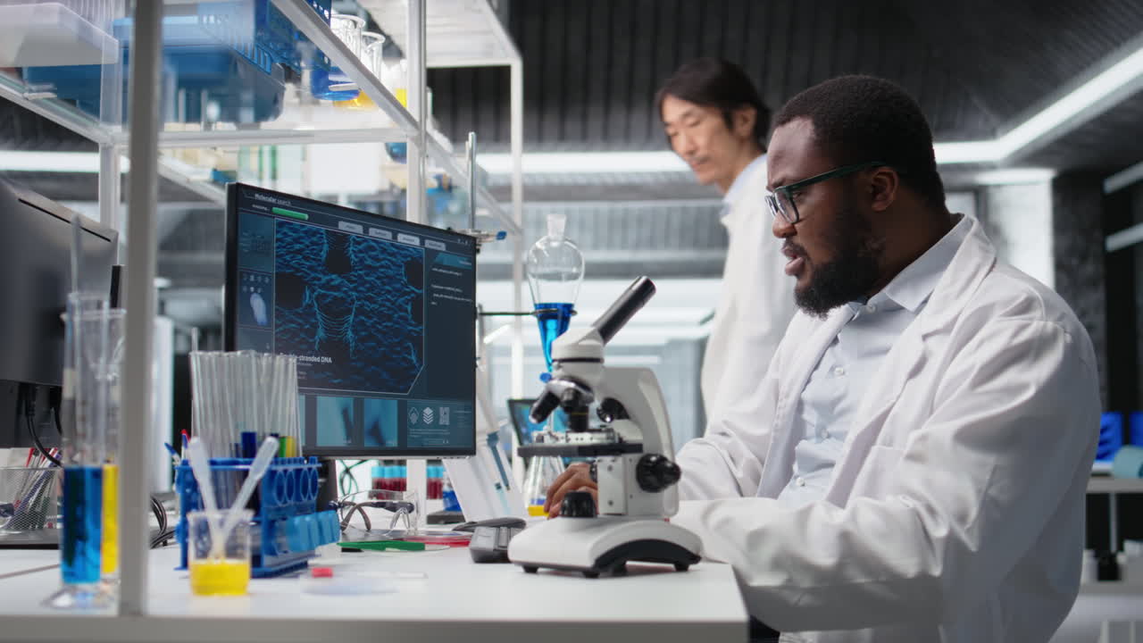 Vertical video Microbiologist in lab inspects slide using optical device, analyzing on PC