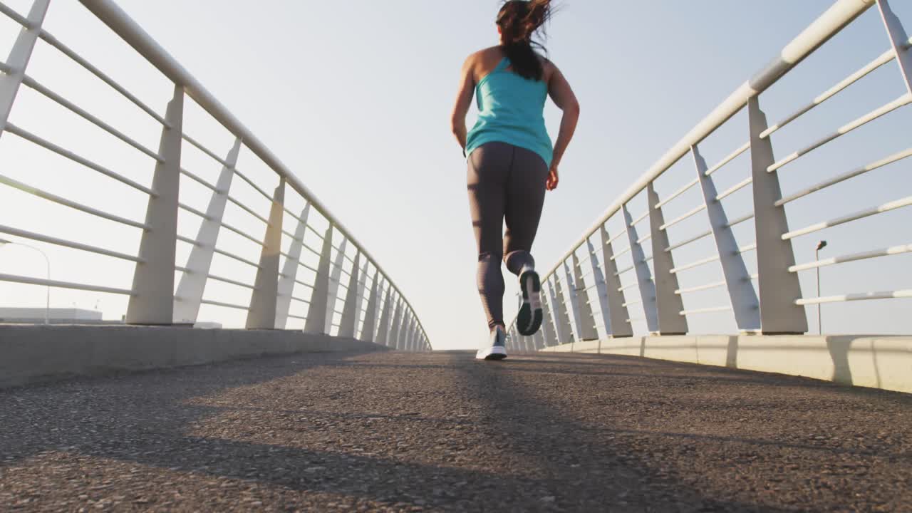 mujer joven corriendo por un puente