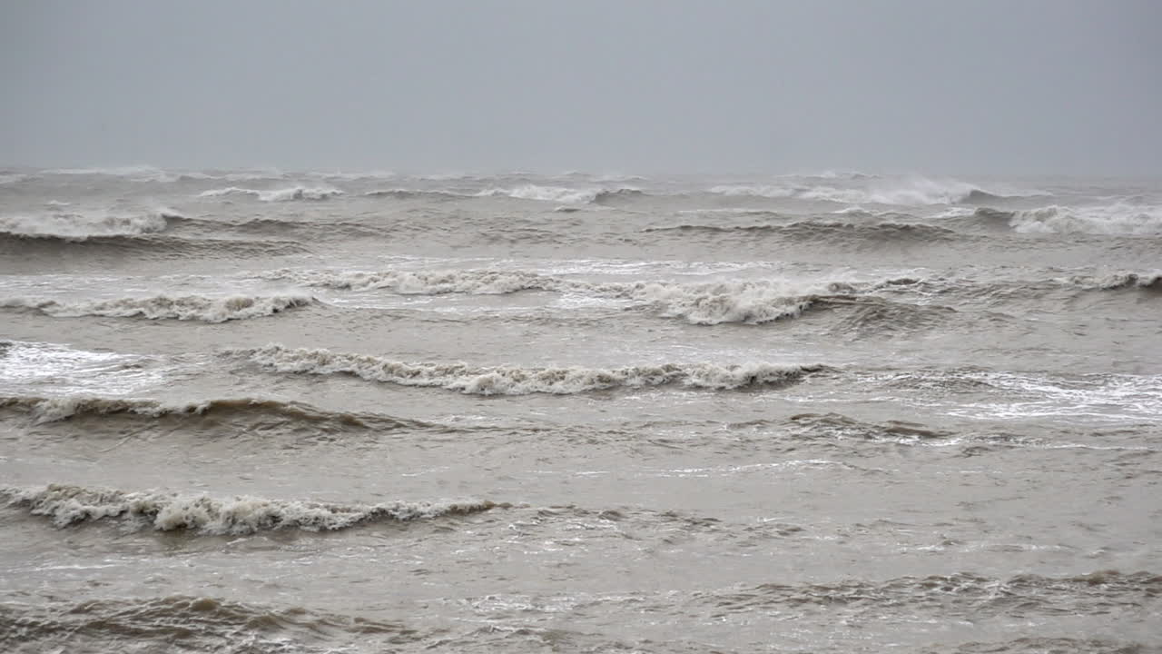 In slow motion dark, moody and threatening large waves are whipped up by strong winds as storm Ciar&aacute;n makes landfall and a bird struggles to fly