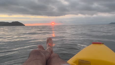 jugando con el agua mientras flota con el kayak en medio del mar, observando la puesta de sol y las islas