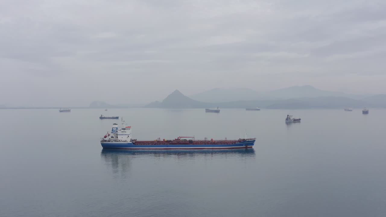 흐린 날 먼 거리에 산등성이가 있는 고요한 날씨에 정박지 대기 지역에 있는 배들