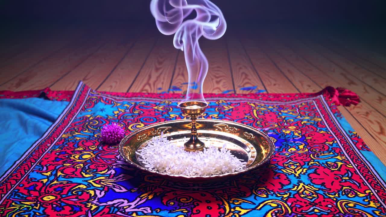 Incense burner emits swirling smoke above a decorative plate filled with rice, creating a serene atmosphere on a vibrant patterned fabric
