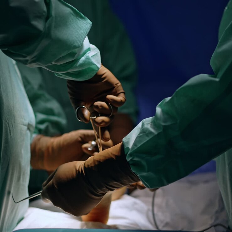 A few pairs of hands in brown latex gloves working with medical tools. Hands of unrecognized surgeons performing operation