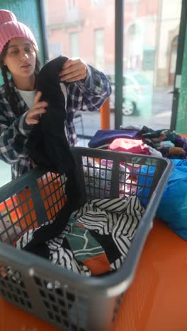 mujer clasificando ropa en un centro de donación