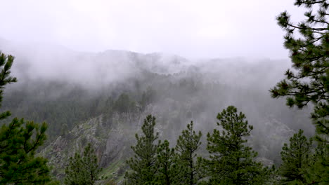 Mountain-fog-thin-mist-moves-over-rocky-forested-mountain,-moody-weather