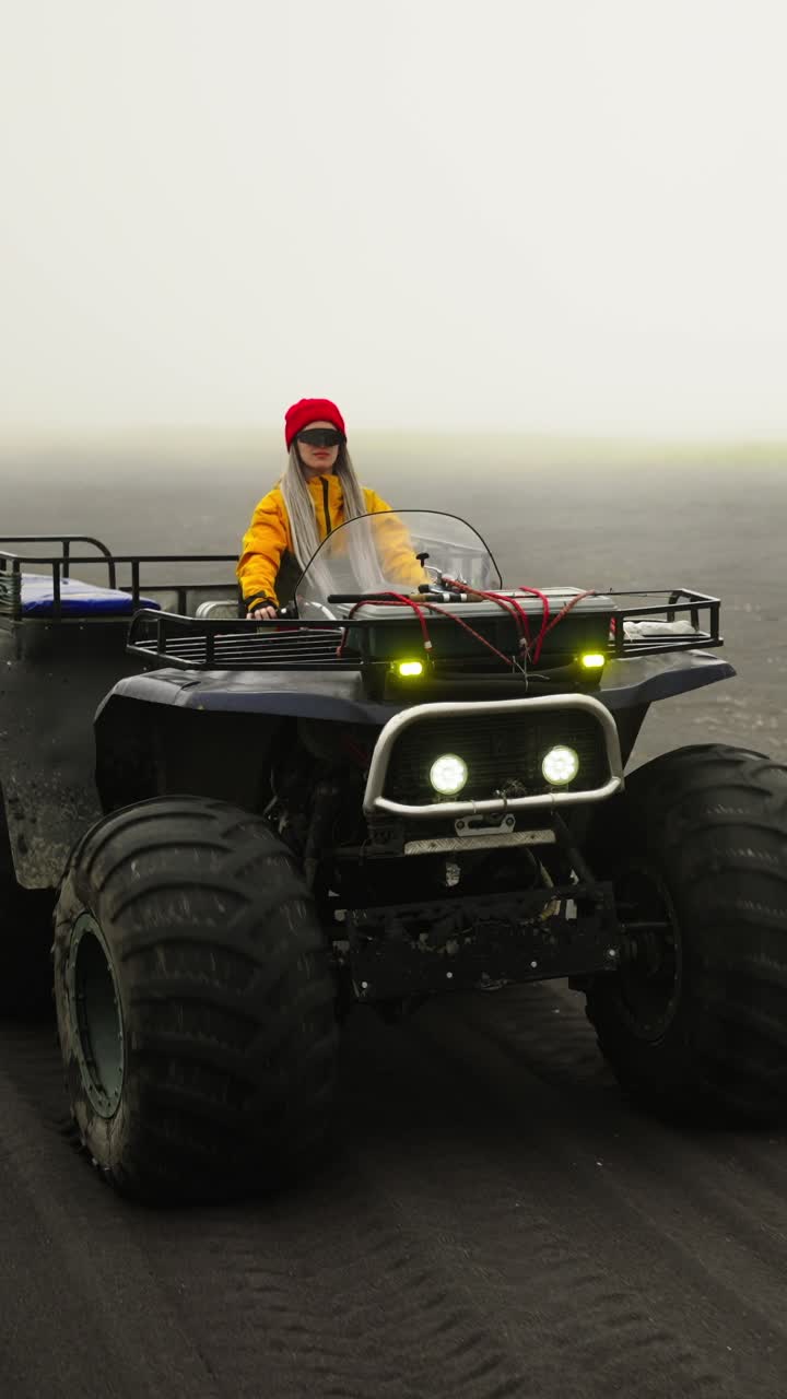 Donna alla guida di un quad su un paesaggio di sabbia nera nebbioso