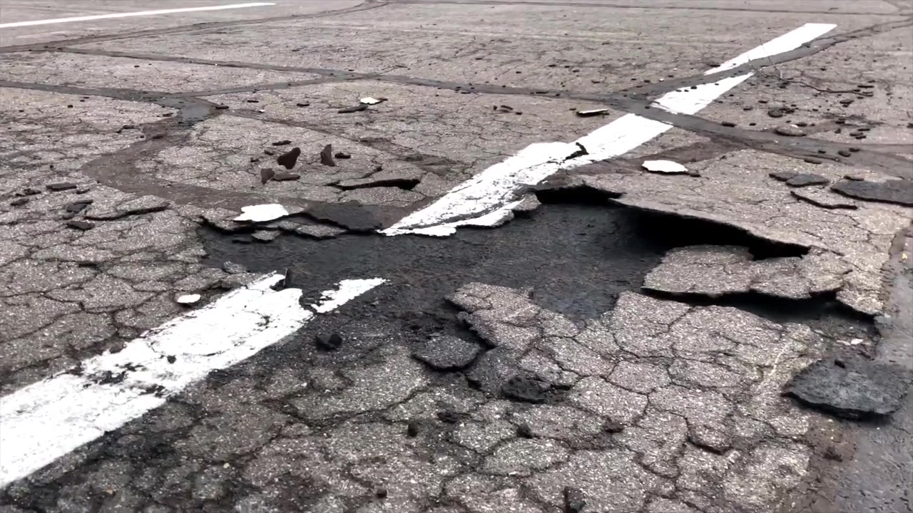 Sigillante bituminoso che si stacca dal parcheggio con soffiatore a zaino.