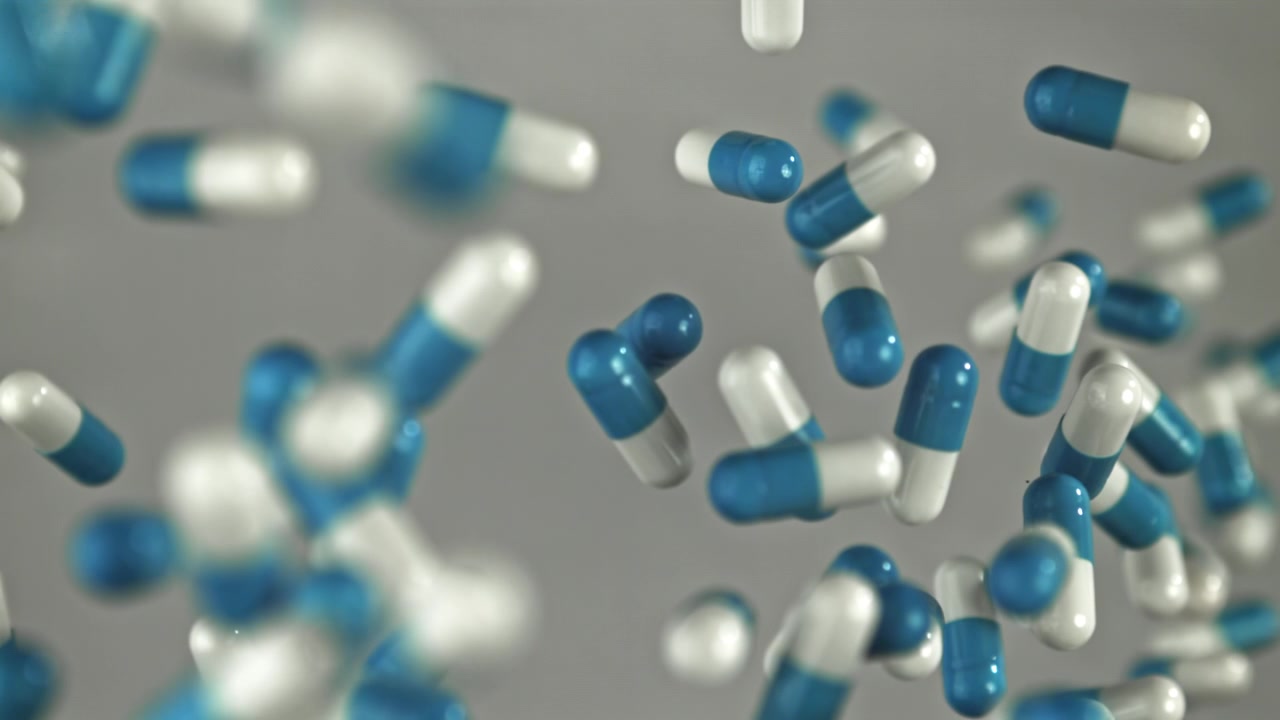 Capsule mediche blu e bianche che cadono al rallentatore