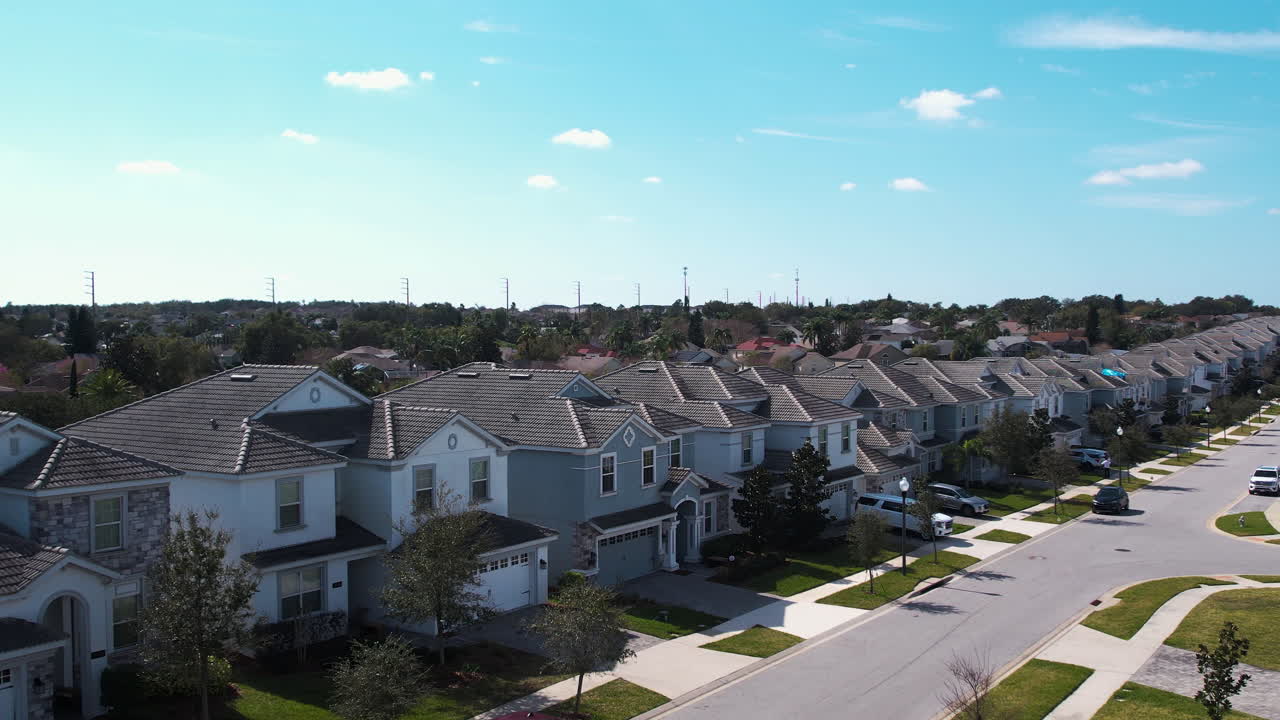 Aerial view rising behind palm trees revealing houses in a neighborhood of Orlando, sunny day in Florida, USA