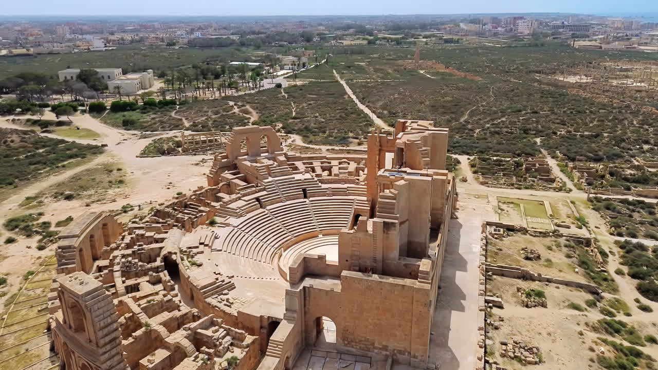Aerial drone view of the magnificent Roman Theatre of Sabratha, highlighting the detailed columns, arches, and stage area of the ancient structure