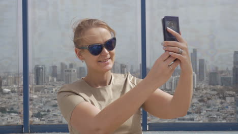 Lächelnde-Frau,-Die-Aus-Der-Höhe-Ein-Handyfoto-Vor-Der-Aussicht-Auf-Tel-Aviv-Macht