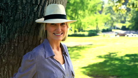 smiling woman leaning against a tree