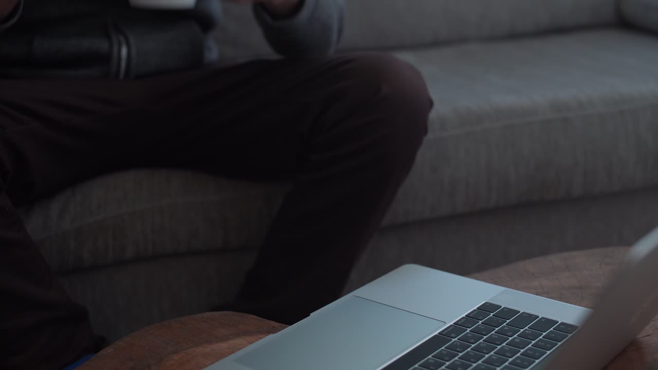 Man works on computer while holding a mug at home
